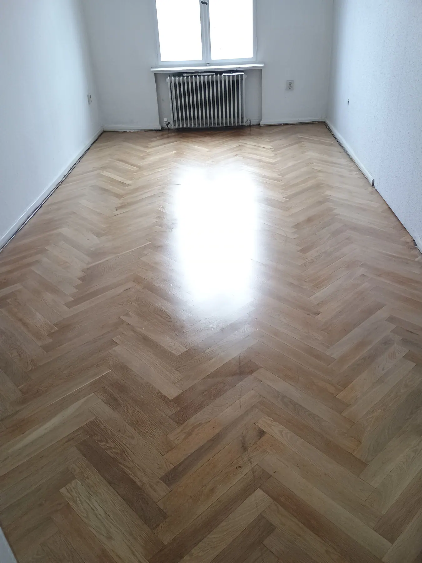Geschliffenes Fischgrätparkett im leeren Wohnraum